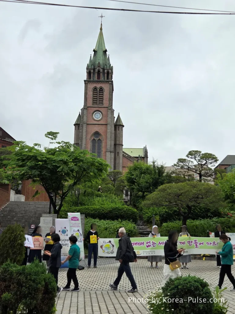 Myeongdong Cathedral grounds with nuns and church members holding an outdoor gathering in front of the cathedral facade