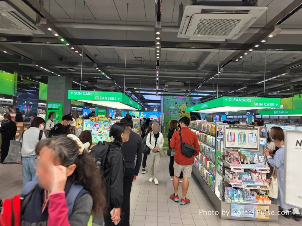 Spacious first floor interior of Olive Young Myeongdong Town with international shoppers browsing skincare products in wide bright aisles
