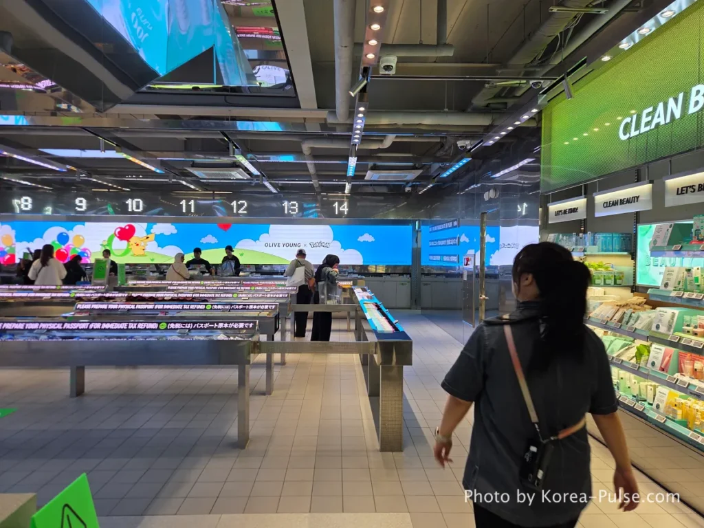 Wide angle view of the massive checkout area on the first floor of Olive Young Myeongdong Town with multiple register counters and multilingual signage in English Japanese and Chinese