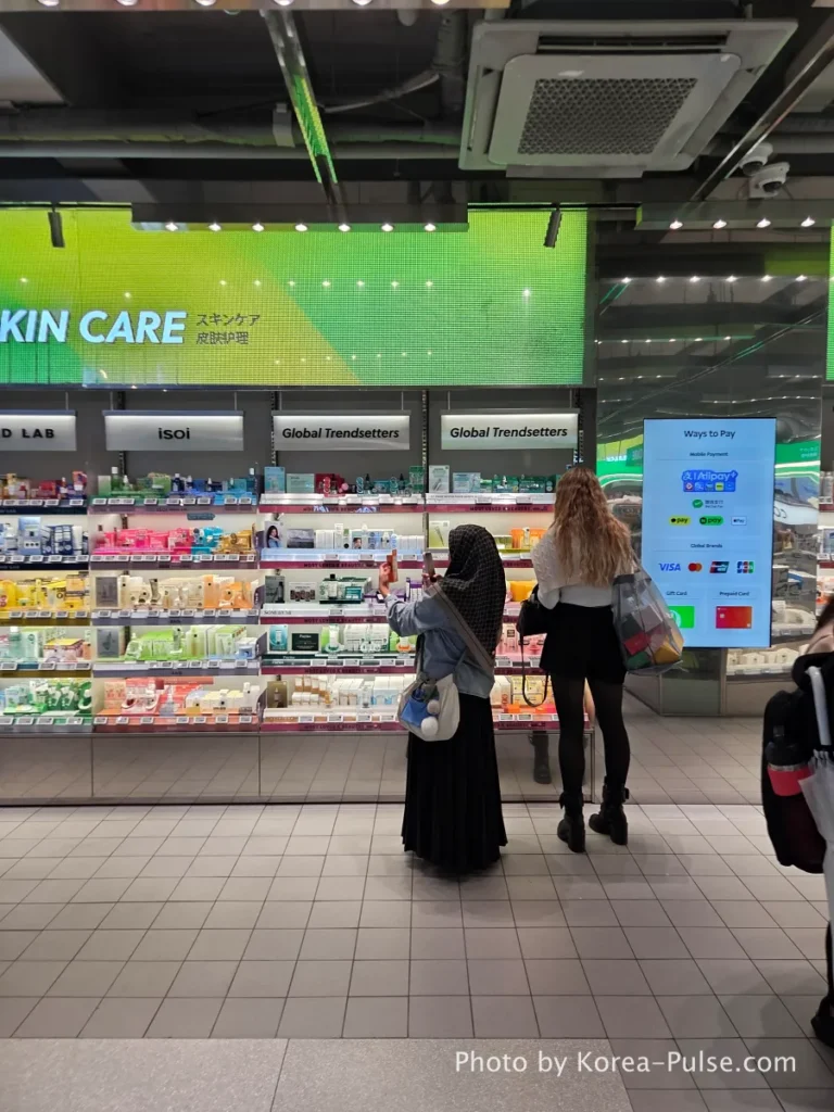 Olive Young Myeongdong Town first floor Skin Care section with products displayed under bright green signage and shoppers browsing the shelves