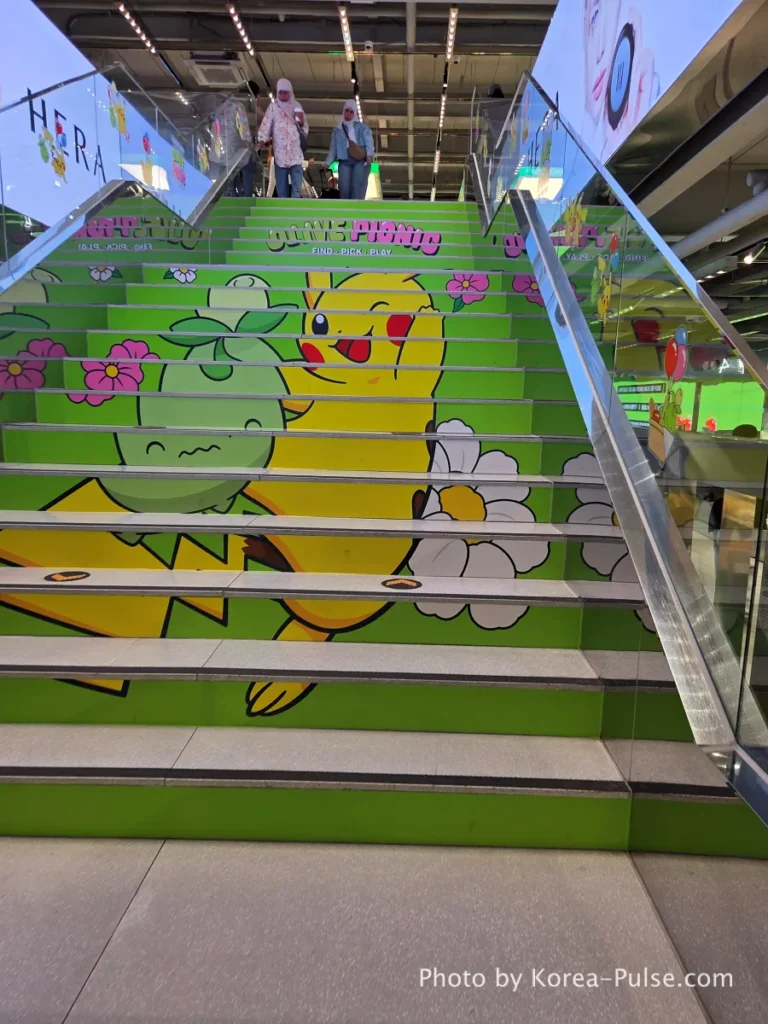 Interior staircase of Olive Young Myeongdong Town decorated with vibrant Pokémon character illustrations leading from the first to the second floor