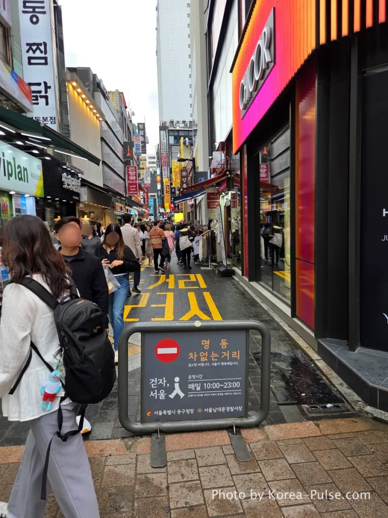 Lively pedestrian-only shopping alley in Myeongdong Seoul filled with tourists and locals browsing restaurants and street food stalls on a busy weekday daytime