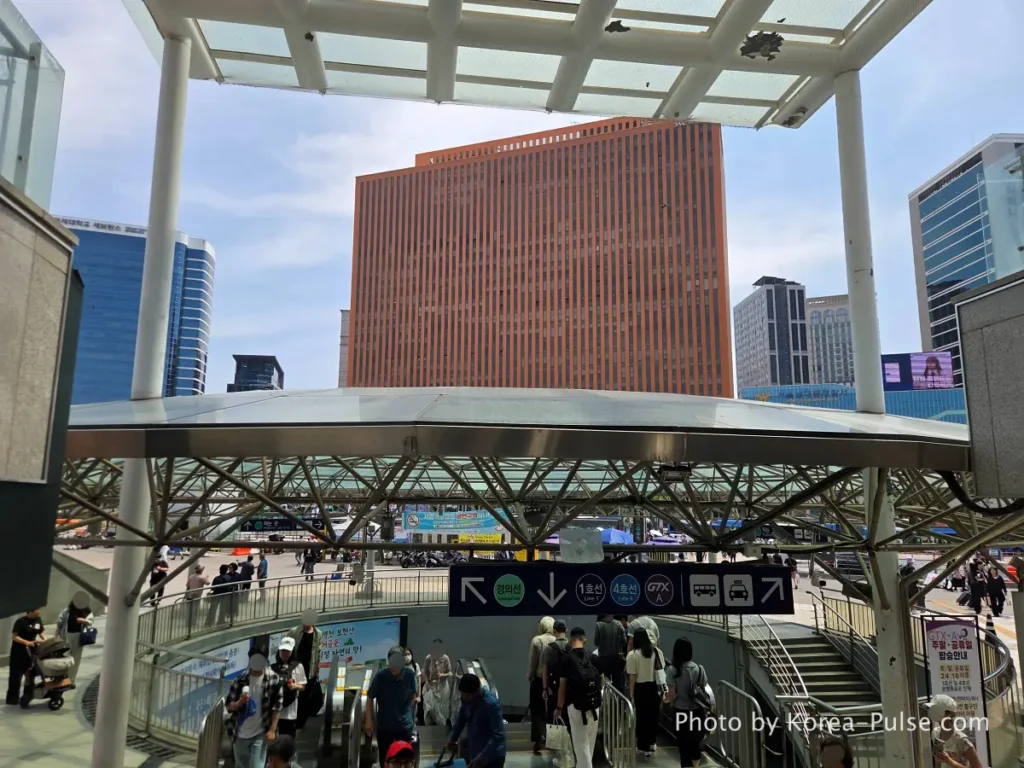 Street level view outside Seoul Station showing the station plaza and the old terracotta company headquarters building