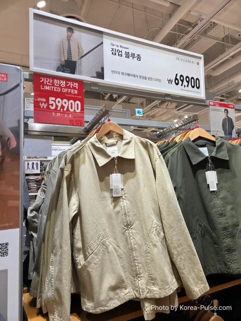 Uniqlo Thank You Festival in Seoul: I Went for One Thing and Bought Another (No Regrets) 7 Uniqlo and JW Anderson Zip-up Blouson (집업 블루종) hanging on a rack in beige and olive green colorways, with a red Limited Offer sign showing the Gamsaje sale price of 59,900 won reduced from 69,900 won