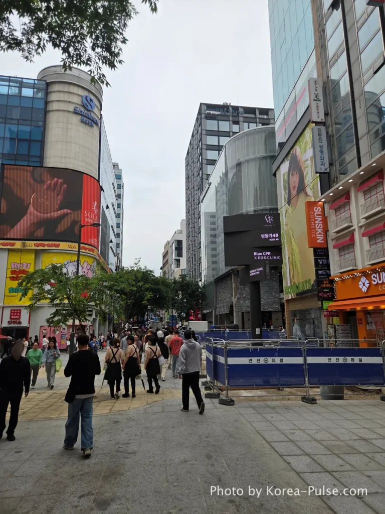 Myeongdong Street in May: Where Seoul's Best Food Hides in Plain Sight 7 Myeongdong street - main shopping street in May 2026 with crowds of pedestrians, large LED billboard, MLB and brand stores visible