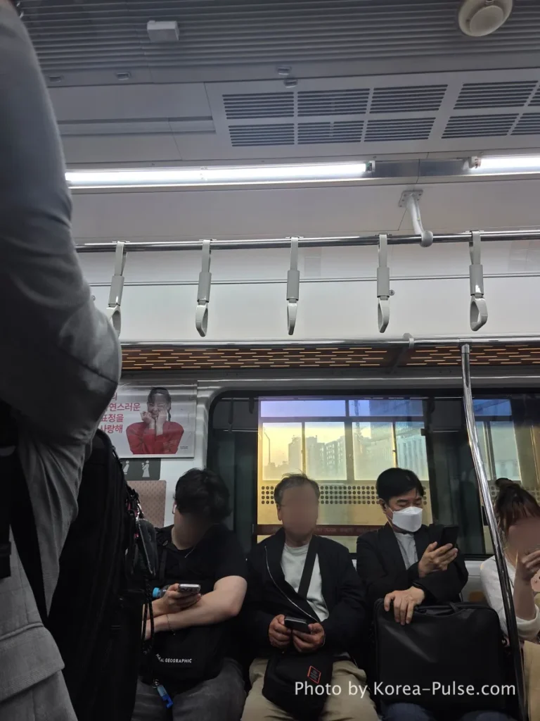 Seoul Metro passengers sitting in silence during evening commute, golden hour light glowing through the train window