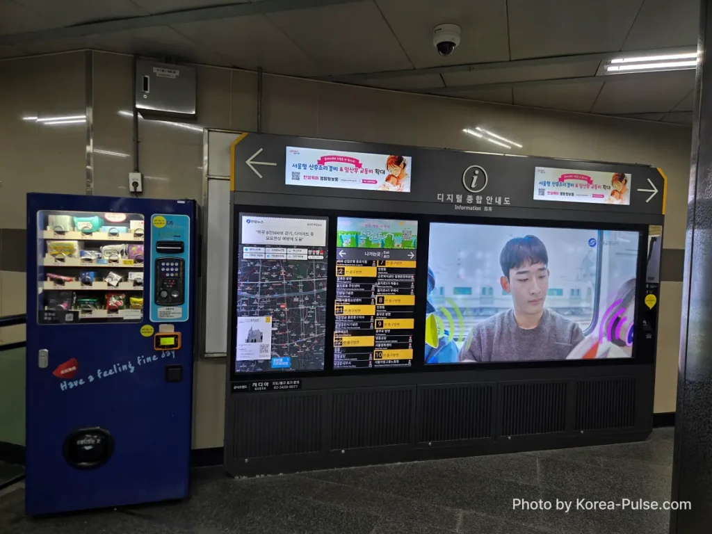 Seoul Metro Line 2 ticket machines and digital information kiosk in Euljiro underground arcade, with beverage vending machines visible nearby