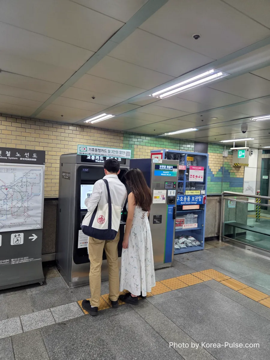 Foreign visitor standing at Seoul Metro ticket machine in Euljiro underground station buying a single journey subway ticket