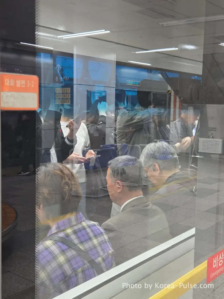 Seoul Metro Line 3 train interior viewed through glass partition, passengers standing during evening commute. Seoul Subway Guide: Rush Hour on Line 3