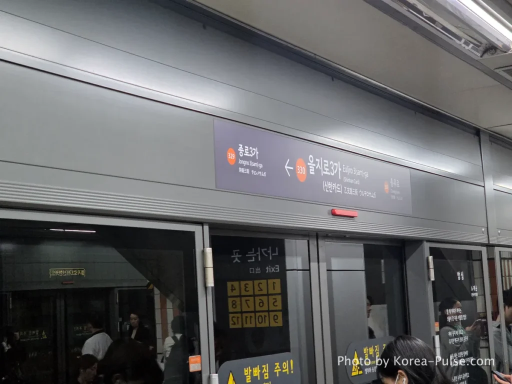Seoul Metro platform screen doors closed during rush hour with train alongside and passengers waiting