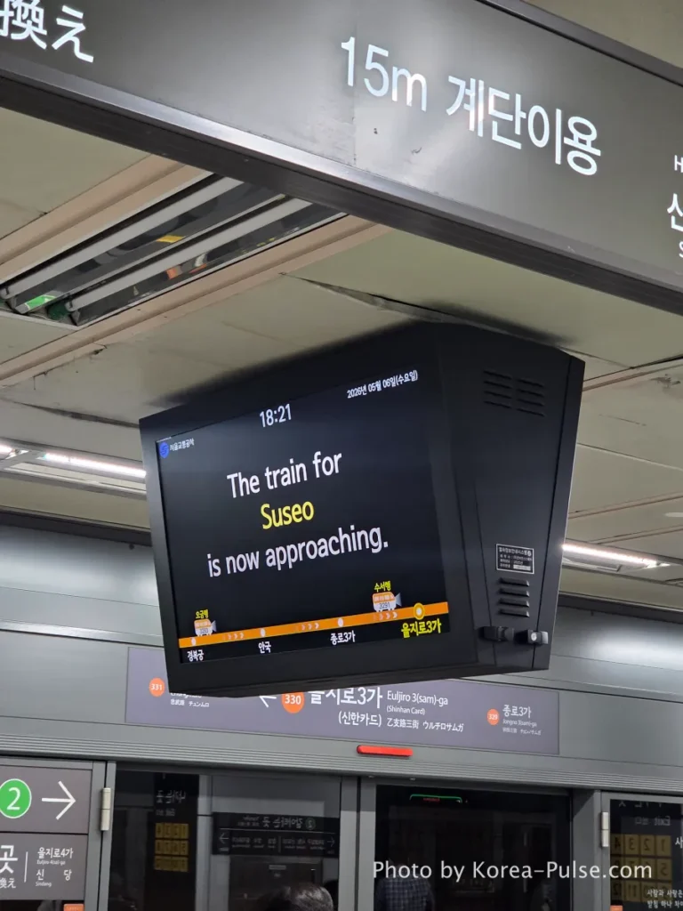 Seoul Metro ceiling displays showing "The train for Suseo is now approaching" alongside Korean wayfinding signage