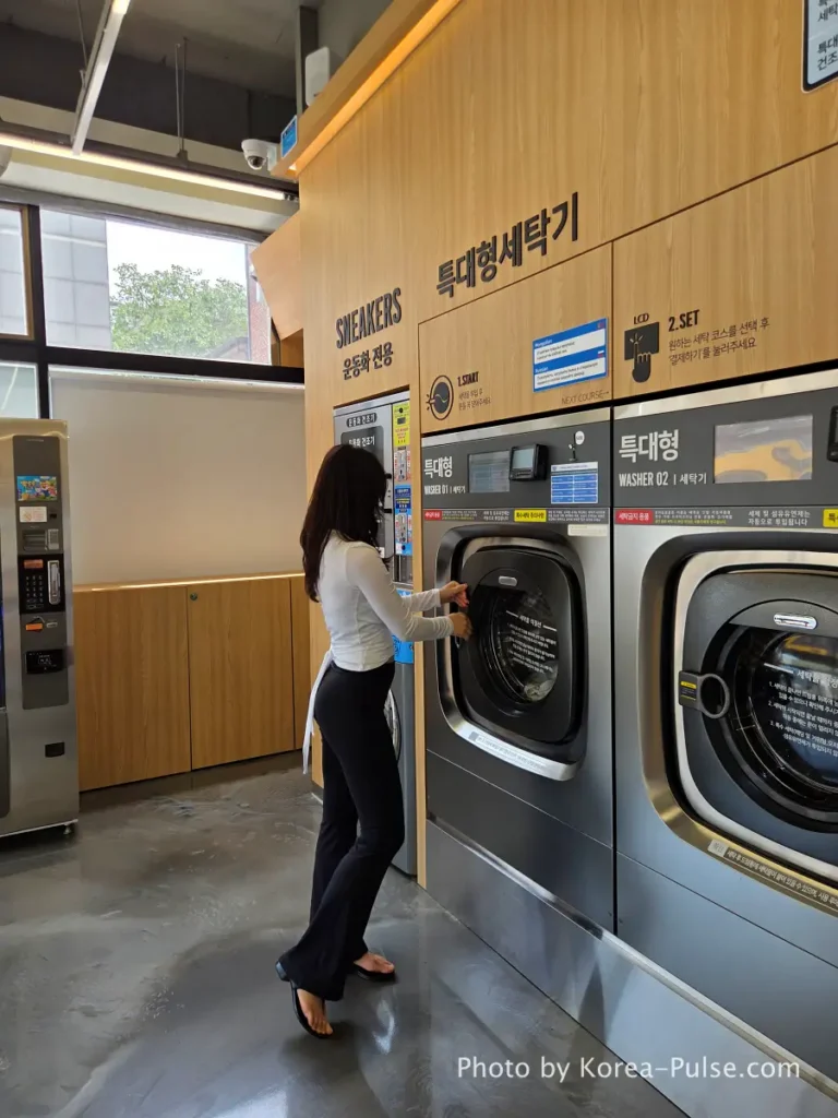 Coin Laundry in Korea: The Local's Complete Guide to 빨래방 1 Woman standing in front of large industrial washing machines at Easy Wash modern coin laundry in Seoul Korea