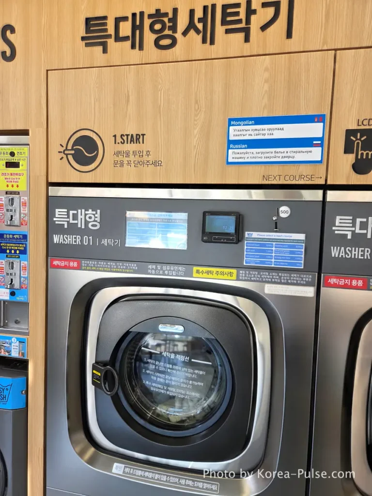 Coin Laundry in Korea: The Local's Complete Guide to 빨래방 7 Large industrial washing machine at Easy Wash Korean coin laundry showing front panel with touchscreen course selection and English price labels on coin slot
