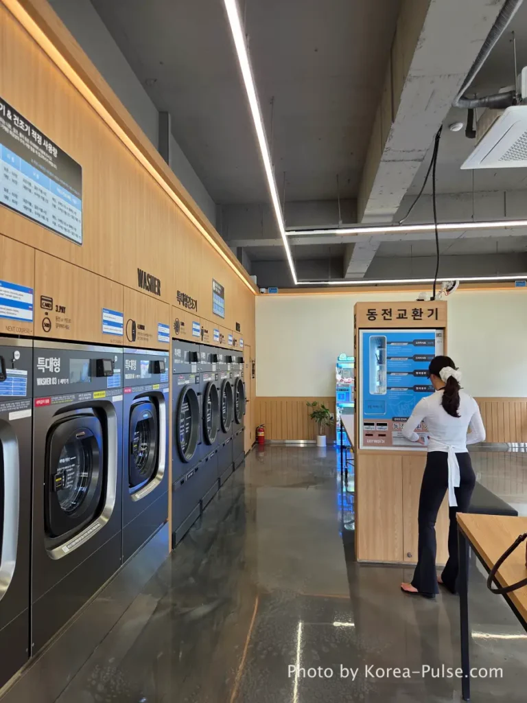Coin Laundry in Korea: The Local's Complete Guide to 빨래방 13 Woman using coin changer machine 동전교환기 at Easy Wash Korean coin laundry to exchange paper bills for 500 won coins needed for sneaker washing station in Seoul