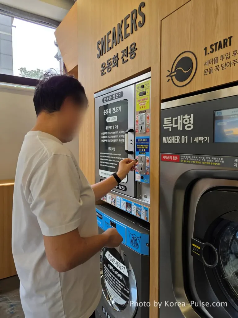 Coin Laundry in Korea: The Local's Complete Guide to 빨래방 12 Close-up of blue coin slot upper panel on sneaker washing machine at Korean coin laundry showing 500 won coins being inserted