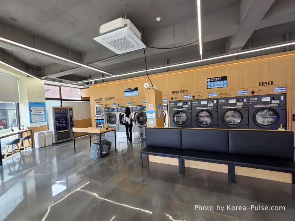 Coin Laundry in Korea: The Local's Complete Guide to 빨래방 5 Interior left side of Easy Wash Korean coin laundromat showing rows of large commercial washing machines with cushioned seating along the wall