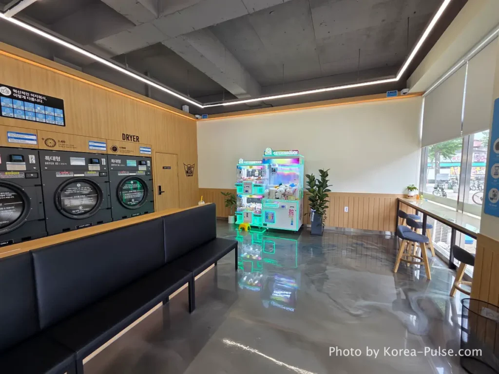 Coin Laundry in Korea: The Local's Complete Guide to 빨래방 6 Interior right side of Easy Wash Korean coin laundromat showing rows of large commercial dryers and capsule toy gacha vending machine in corner