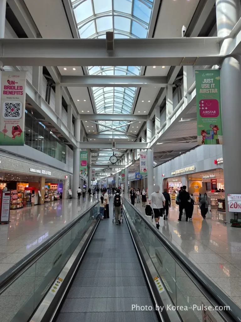 Incheon Airport Terminal 1 airside moving walkway with high glass ceiling and duty-free shops