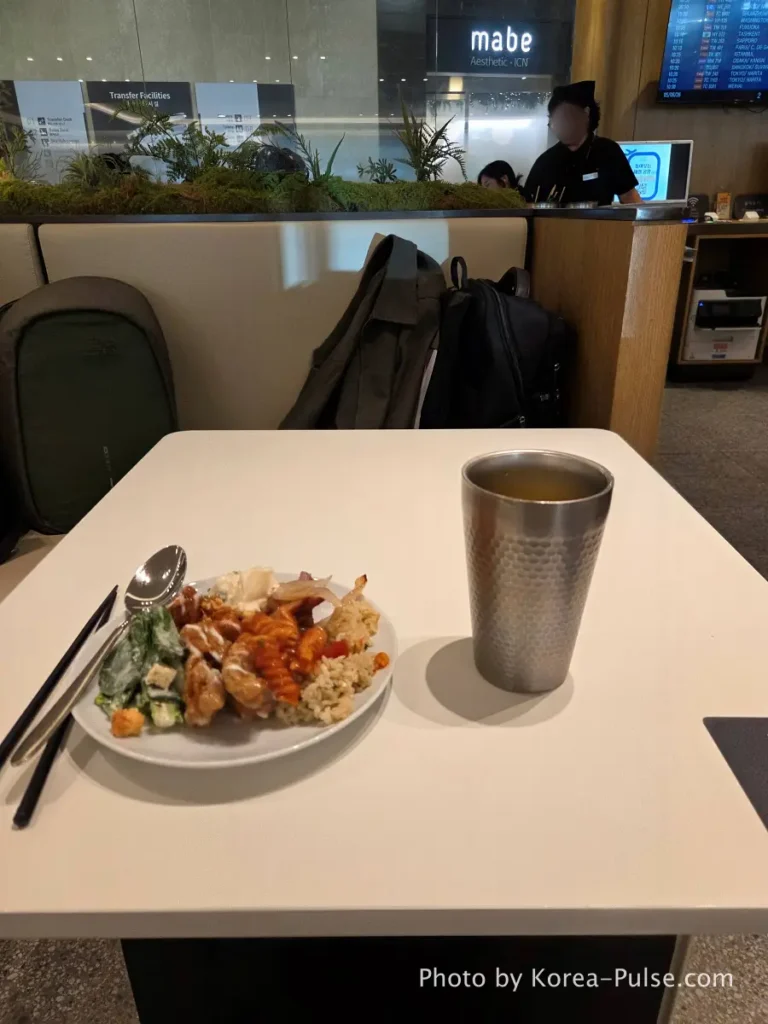 Plate of lounge food and glass of fruit juice at SKYHUB Lounge table Incheon Airport departure