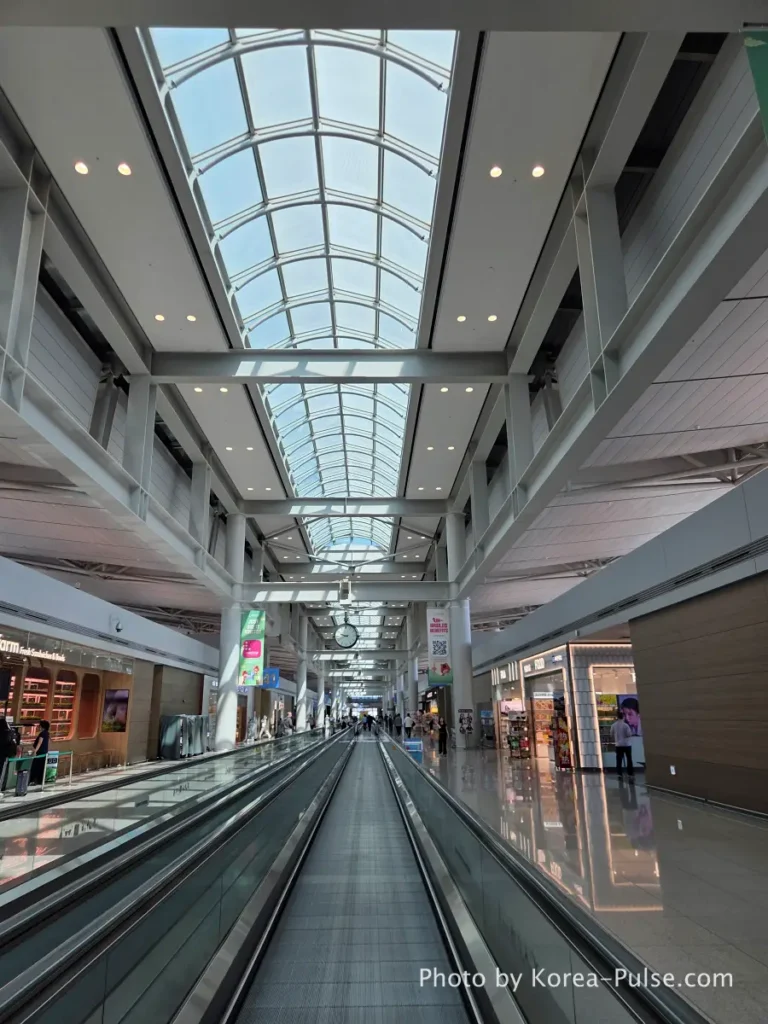 Incheon Airport Terminal 1 gate corridor with high arched glass ceiling and moving walkways toward departure gates