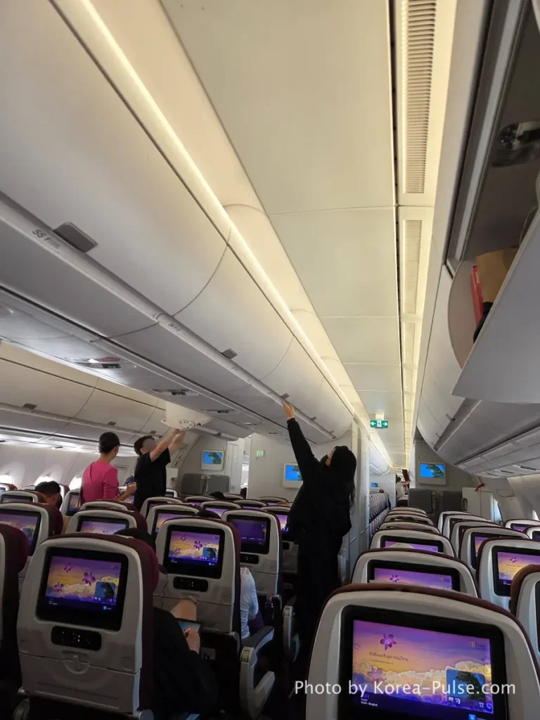 Thai Airways cabin interior with purple seat covers and personal screens showing Thai art before departure