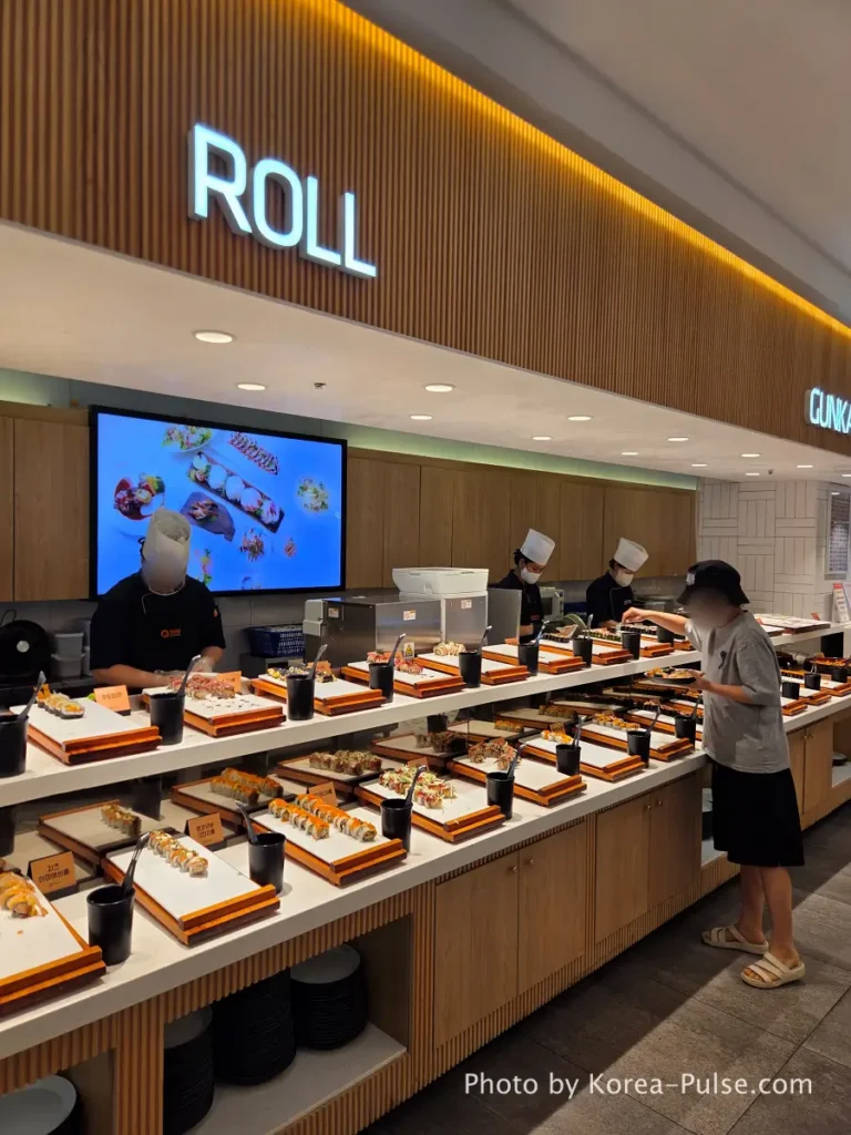 The 120-Dish Question: Inside QooQoo, Korea's Sushi Buffet Phenomenon 16 Roll zone counter with chef preparing sushi rolls at QooQoo