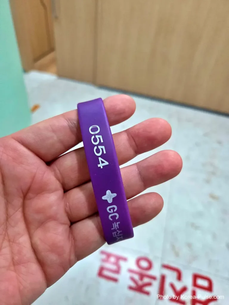 Inside Korea's 2-Hour Health Checkup Machine: Wristbands, Yellow Lines, and a Bowl of Porridge 3 Purple RFID checkup wristband with an ID number, worn on a patient's wrist