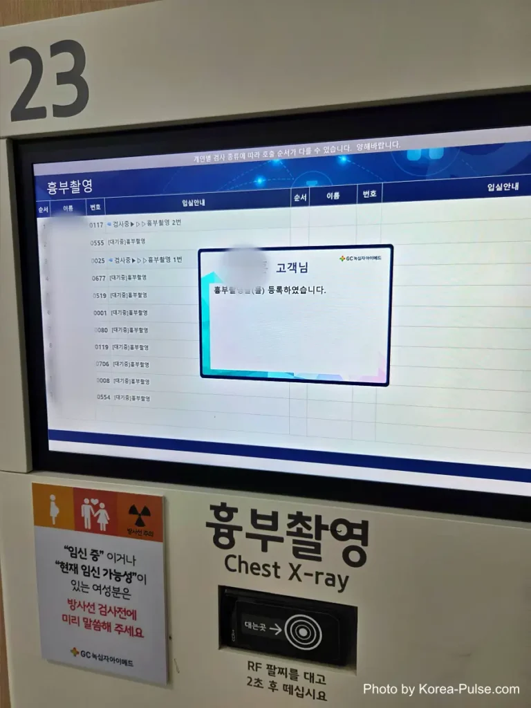 Inside Korea's 2-Hour Health Checkup Machine: Wristbands, Yellow Lines, and a Bowl of Porridge 6 Overhead digital queue monitor above a Chest X-ray examination room showing patient status