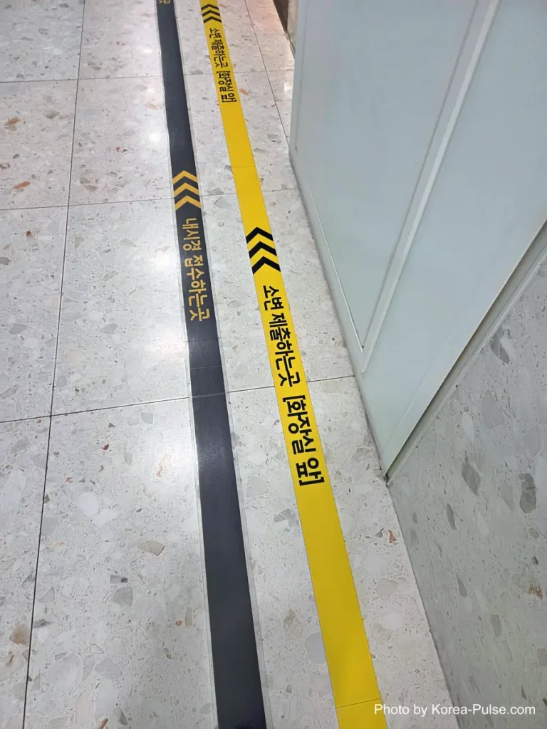 Inside Korea's 2-Hour Health Checkup Machine: Wristbands, Yellow Lines, and a Bowl of Porridge 10 Yellow directional arrows taped on the floor of a hospital corridor