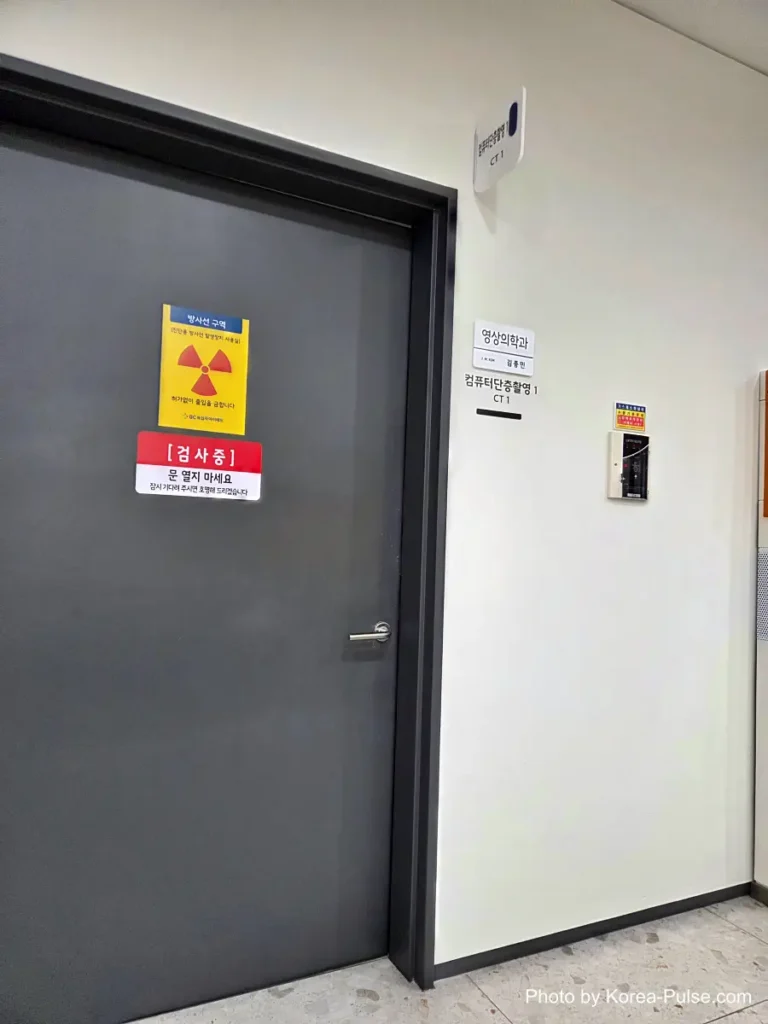 Inside Korea's 2-Hour Health Checkup Machine: Wristbands, Yellow Lines, and a Bowl of Porridge 11 Closed door marked with a yellow radiation warning sign outside a CT scan room