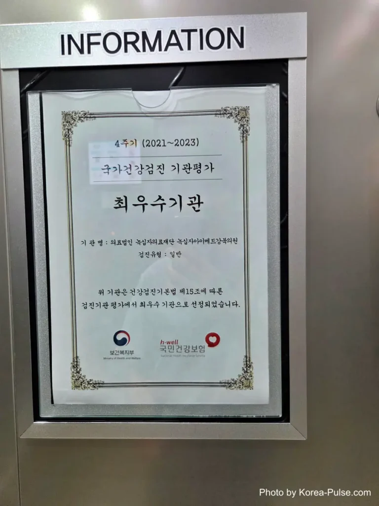 Inside Korea's 2-Hour Health Checkup Machine: Wristbands, Yellow Lines, and a Bowl of Porridge 17 Framed certificate on a wall recognizing a health screening clinic as an excellent institution